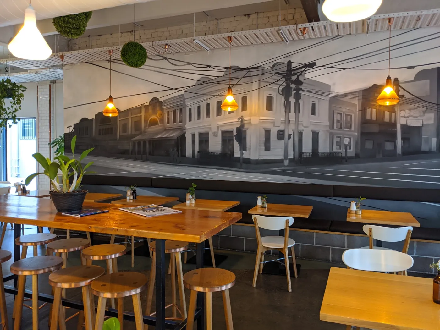 Timber tables and yellow chairs in front of the old Fitzroy streetscape mural