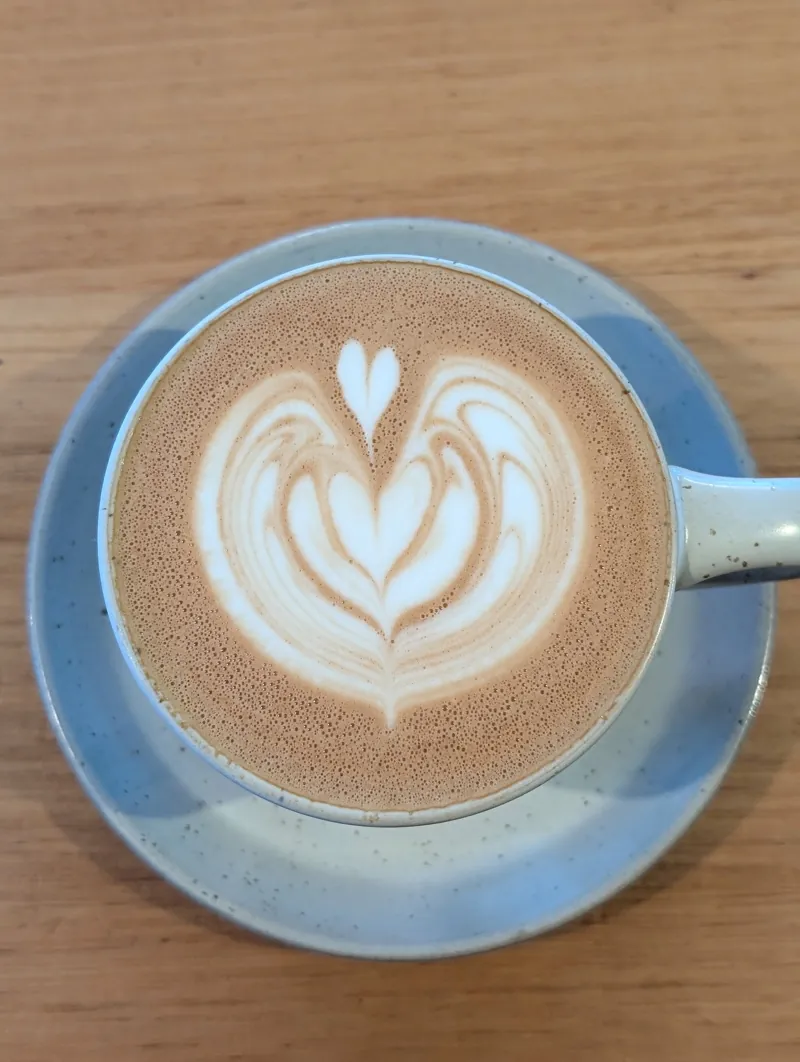 A flat white with latte art in a blue speckled cup