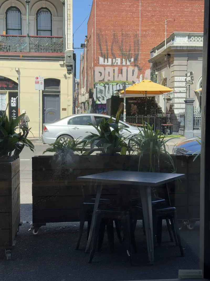 An outdoor table on Johnston St, with street art across the road